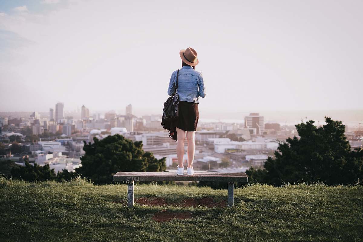 people woman standing on bench facing city skyline during daytime human