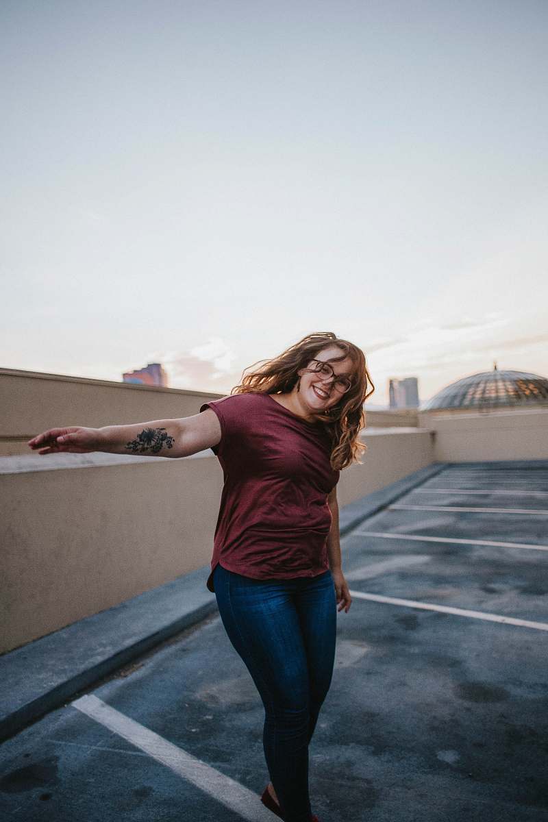 human woman standing on gray concrete floor while raising her left arm people