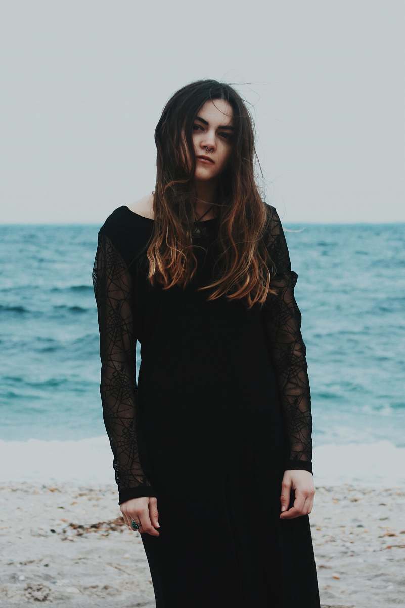 human woman standing on gray sand near the ocean during daytime people