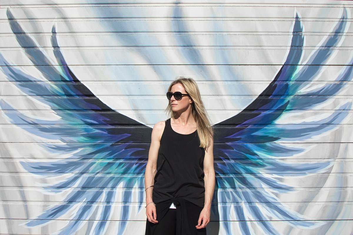 human woman taking photo near wings painted wall people