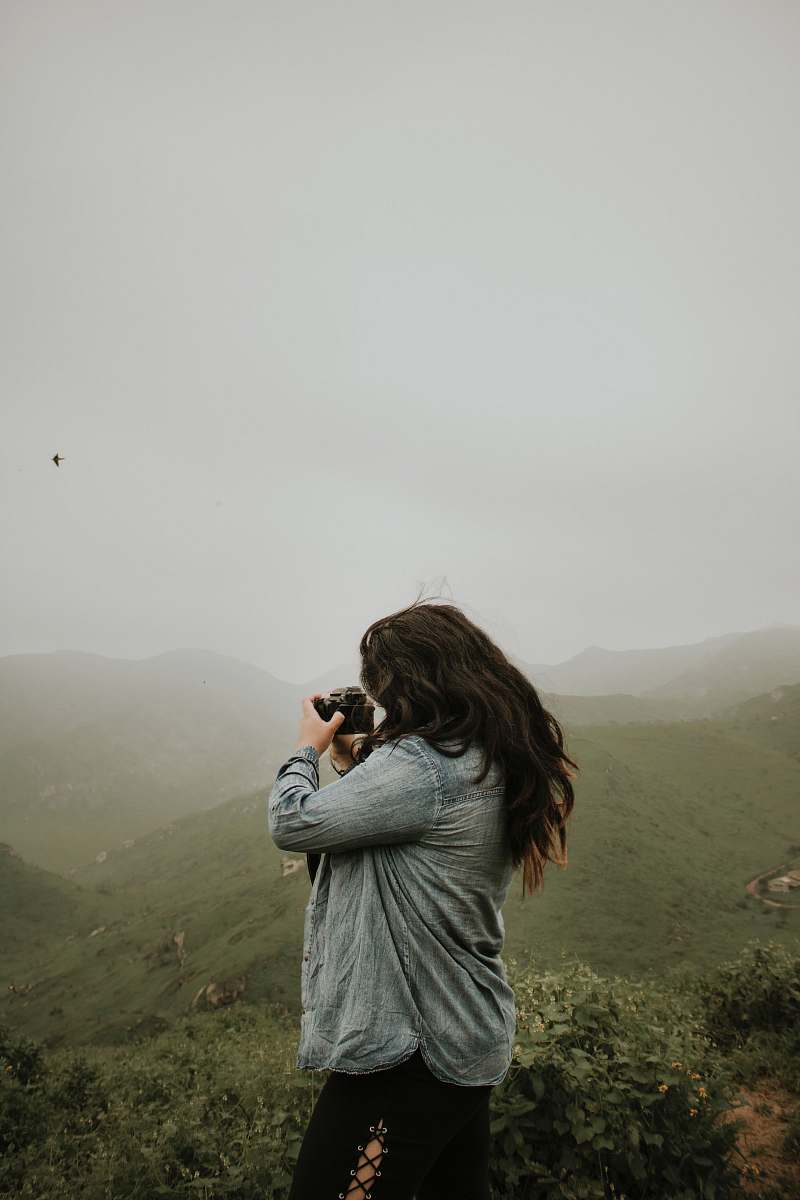 human woman taking photo of mountain during daytime people