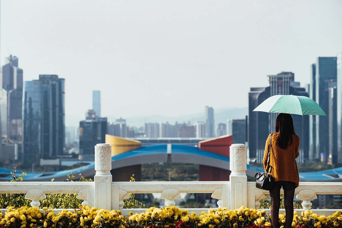 human woman using blue umbrella standing in front of fence people