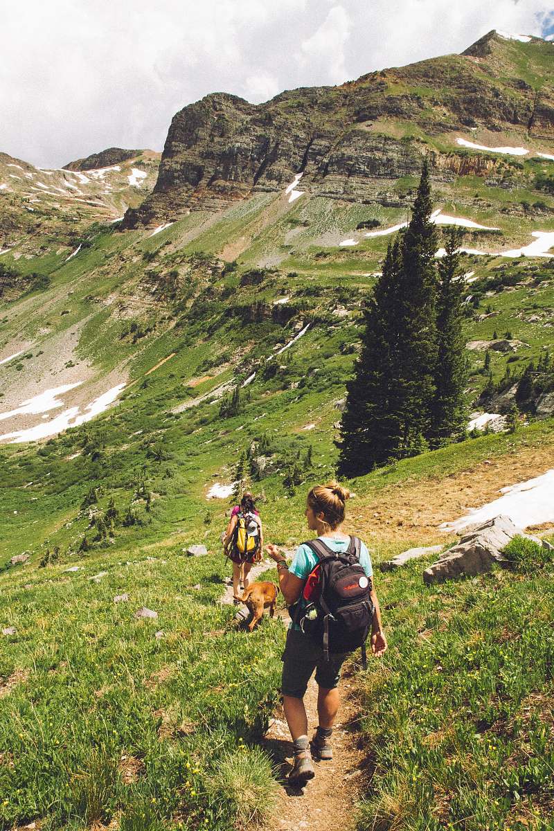 people woman walking down the hill at daytime hiking