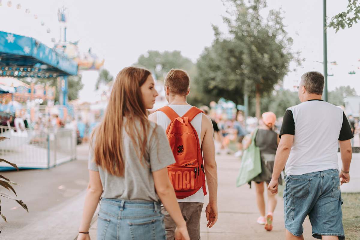 human woman walking near two men in pathway during daytime people