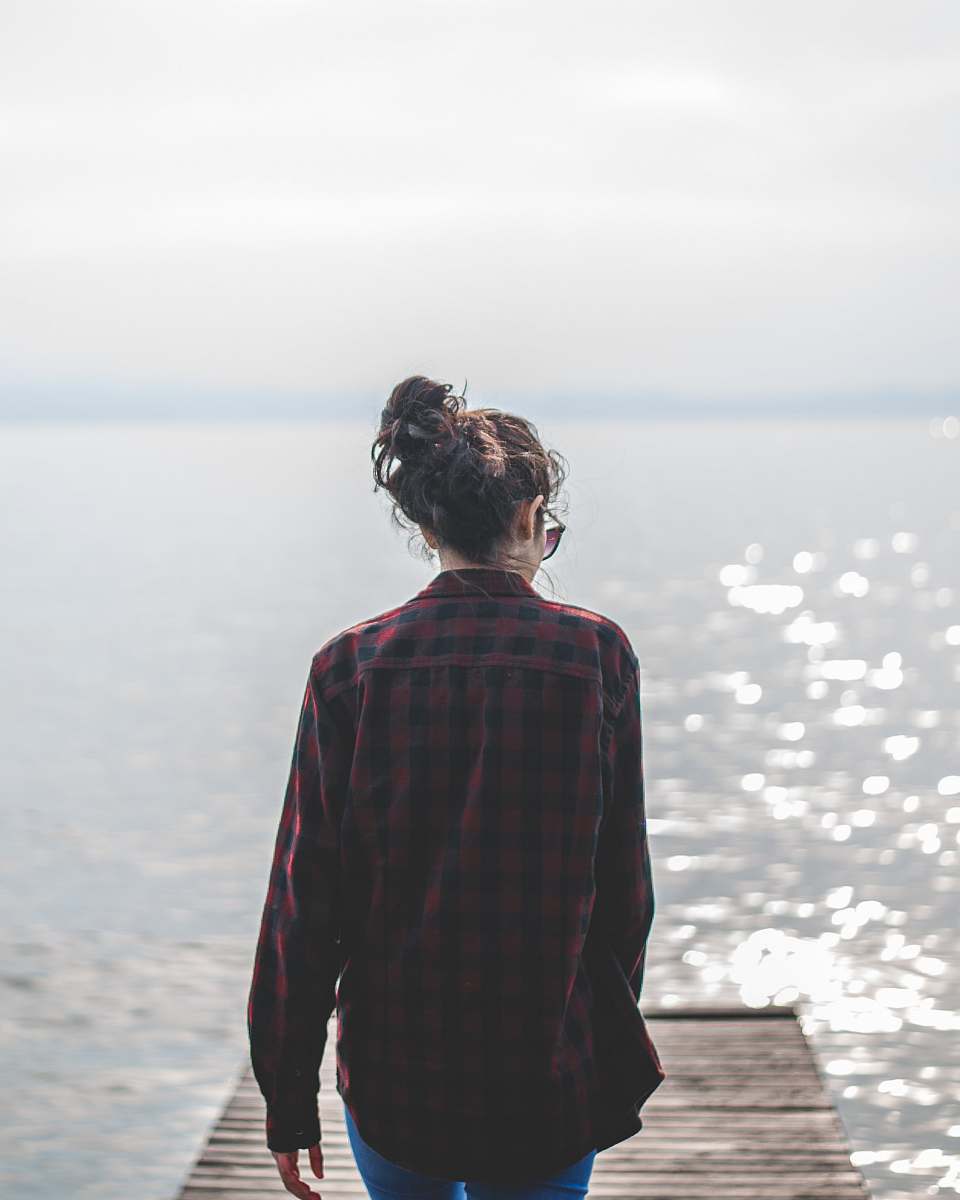 human woman wearing black and red gingham walking on wooden dock people