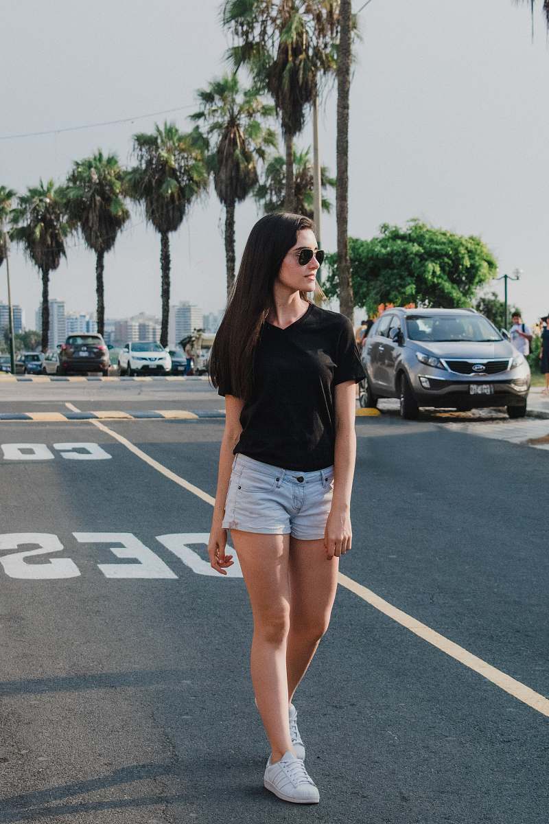 human woman wearing black V-neck shirt and blue shorts standing on gray concrete road people