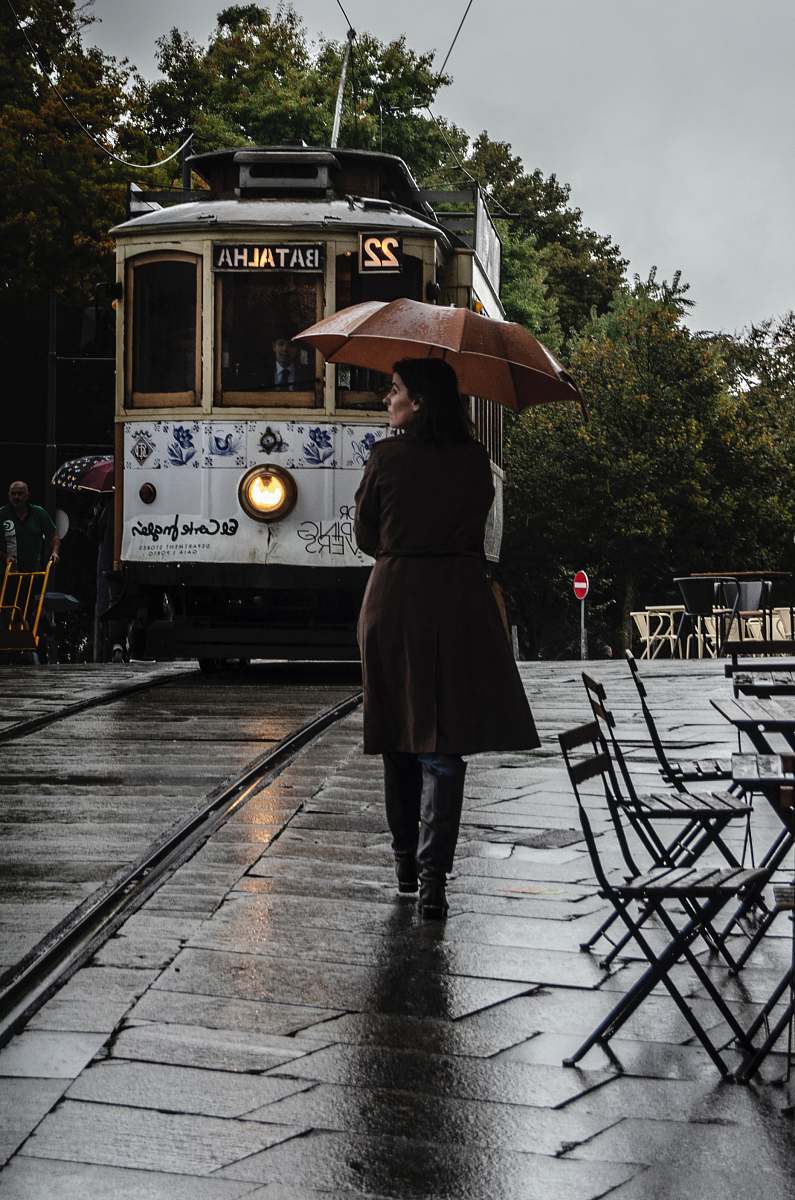 human woman wearing brown coat walking on street while holding umbrella people