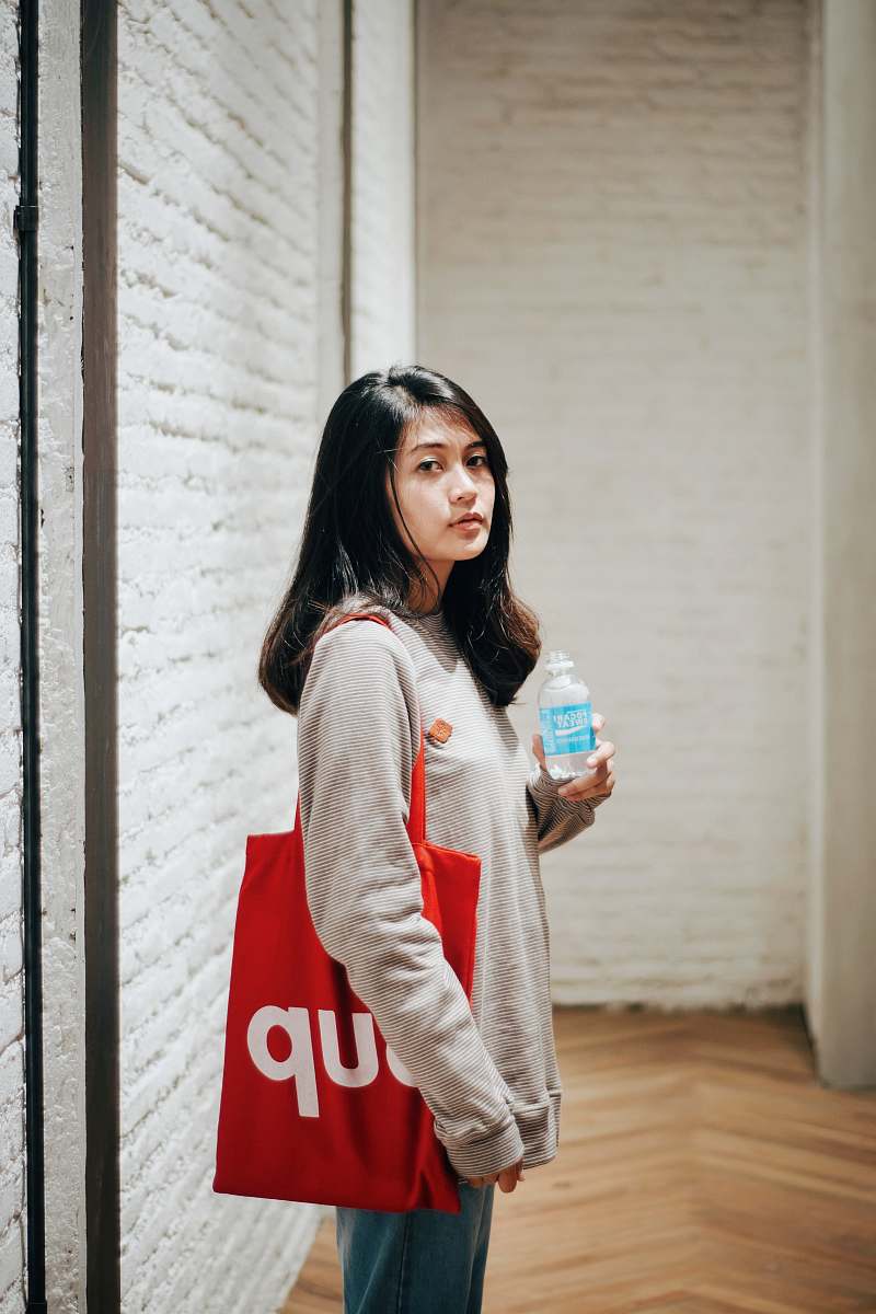 human woman wearing grey shirt with Supreme tote bag people