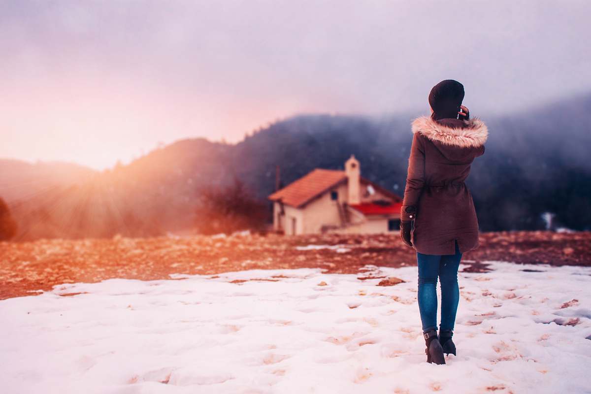 human woman wearing parka hoodie standing in front of house people
