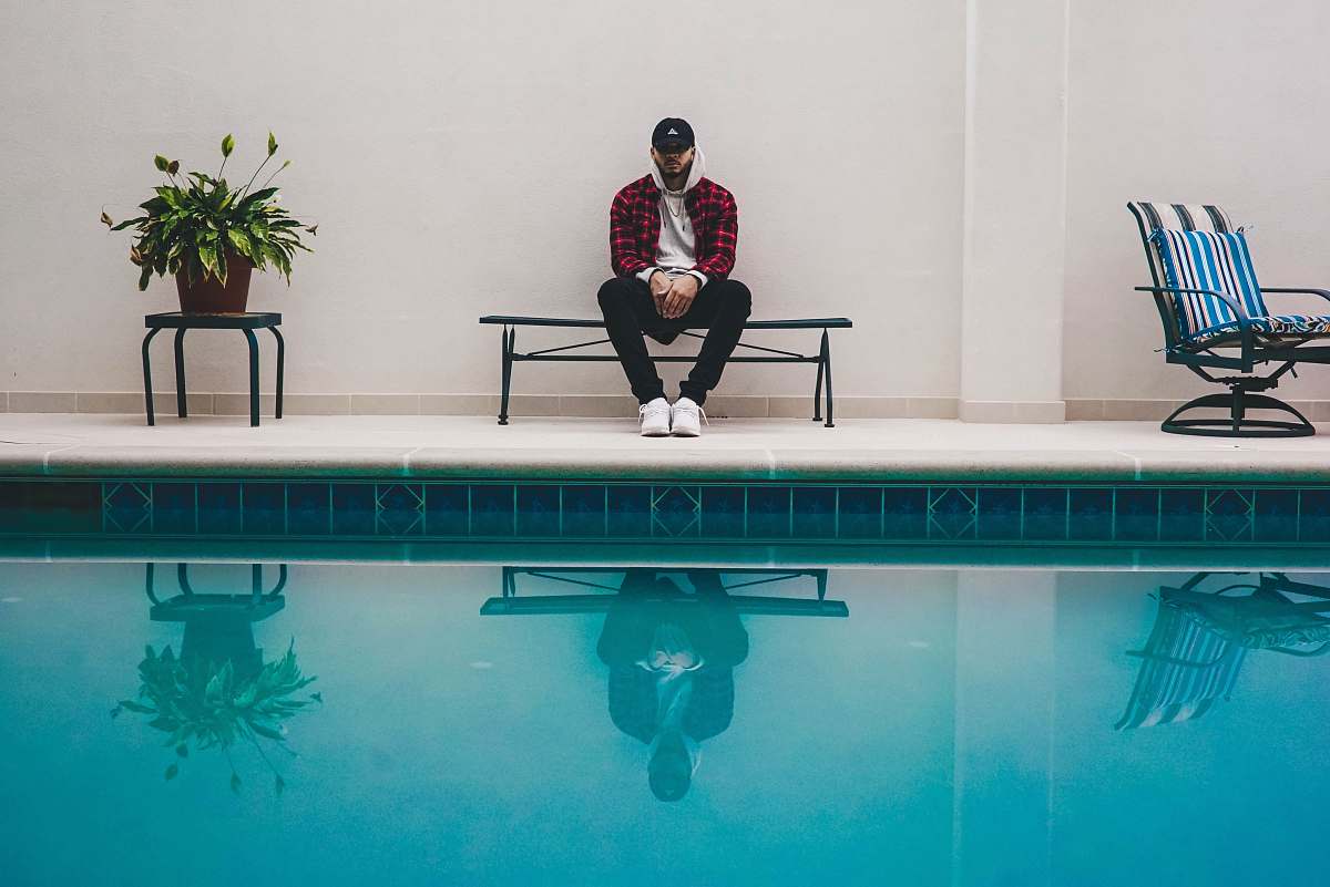 people man sitting on black bench near pool person