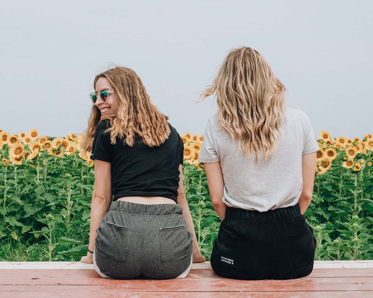 blonde two women's sitting in front of sunflowers female