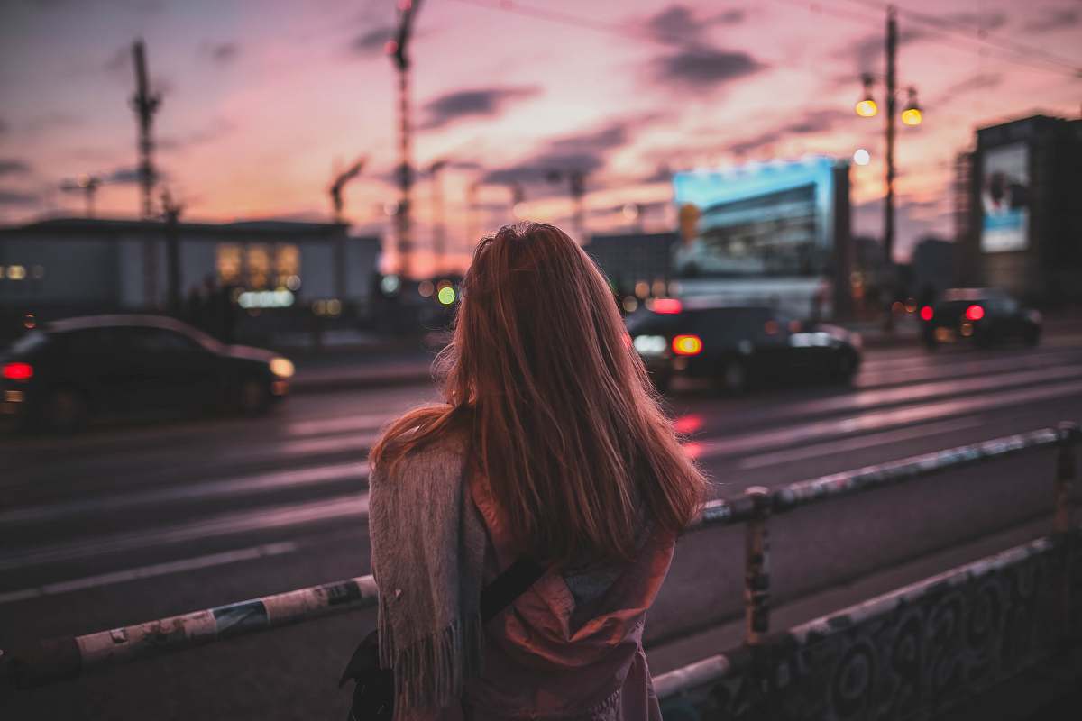 car woman standing on rail facing road at dusk woman