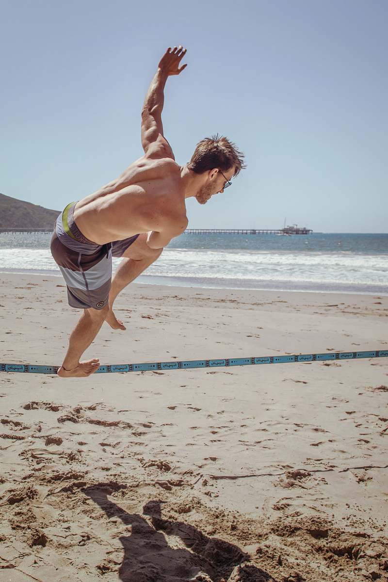 clothing man in sunglasses and board shorts walking on rope shorts