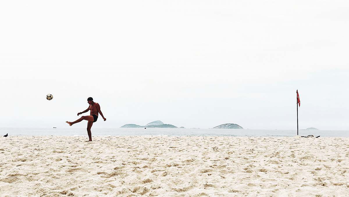 clothing man playing soccer on beach shorts