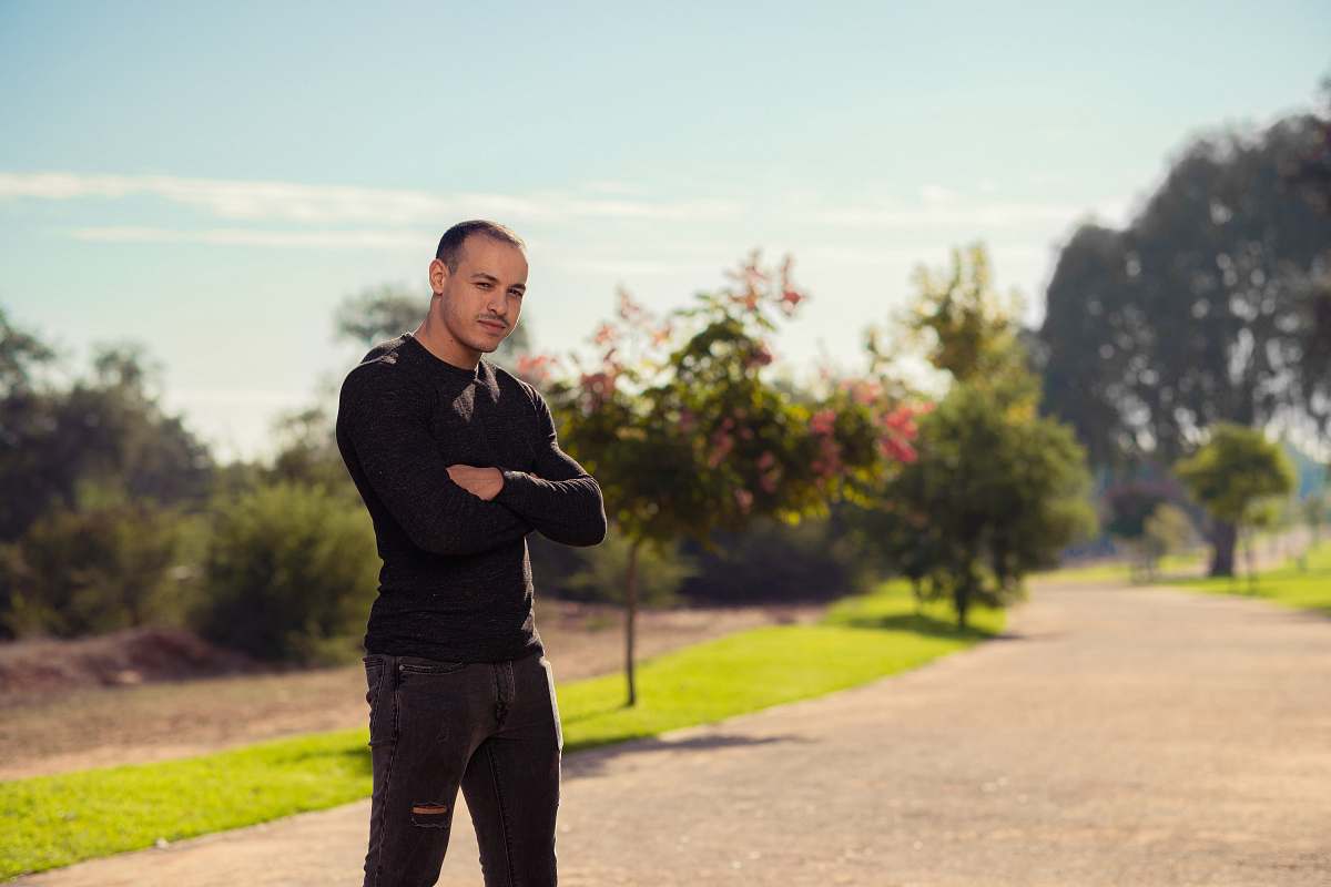 human man standing on pathway with trees during daytime person
