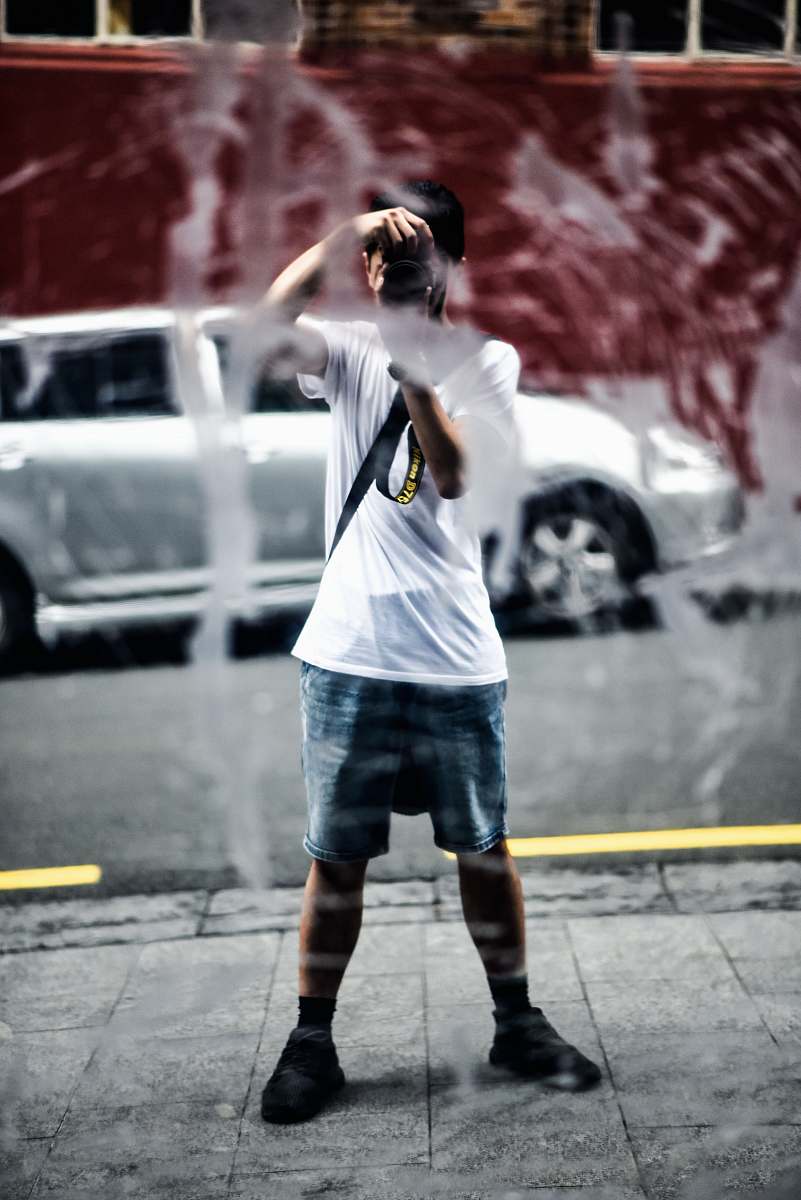 clothing person in white t-shirt with blue and white shorts taking photo using camera shorts