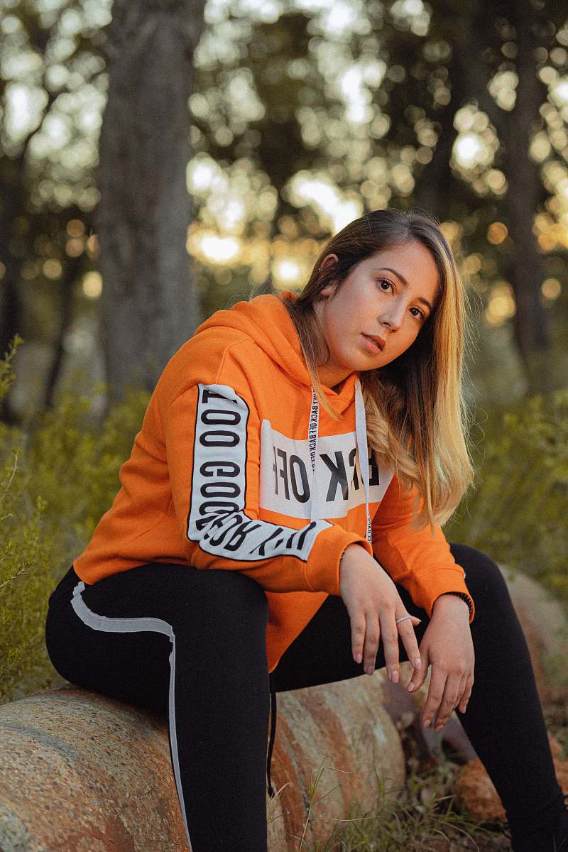 clothing woman sitting on log in orange hoodie sweater