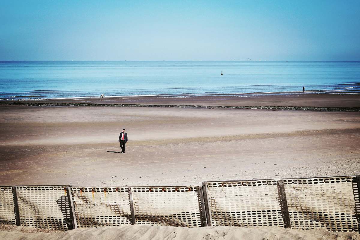 sea man walking at the coastline near white fences coast