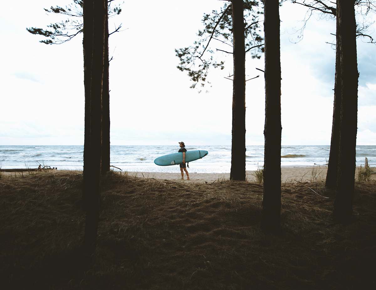 ocean person standing while carrying blue surfboard near sea during daytime coast