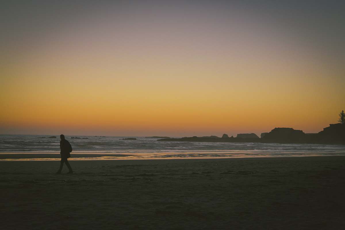 coast silhouette of person walking on seashore water