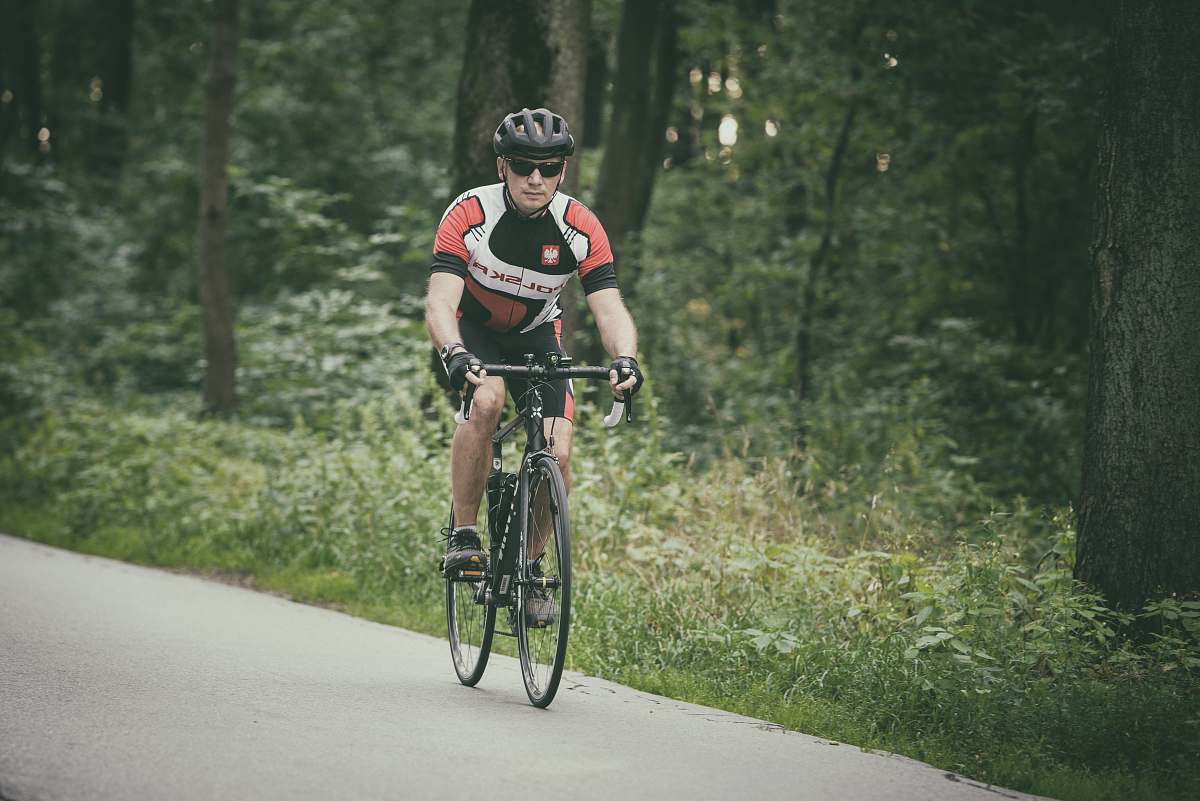 bike man riding bike at the road near trees during day transportation