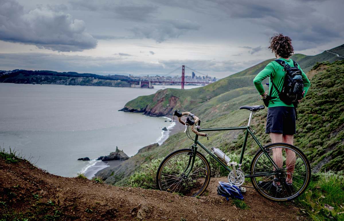 bicycle man standing beside bike on top of mountain mountain bike