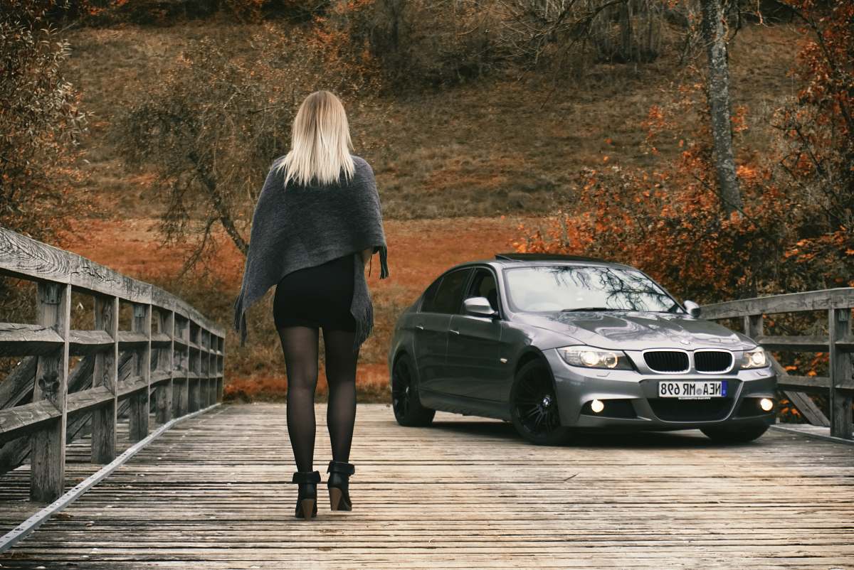 car woman walking through gray BMW car at the bridge woman