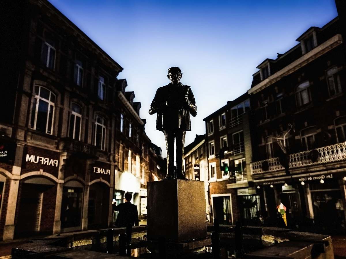 city man standing statue in between buildings town