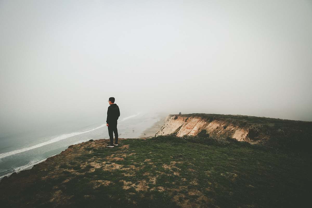 solitude man standing on cliff coast