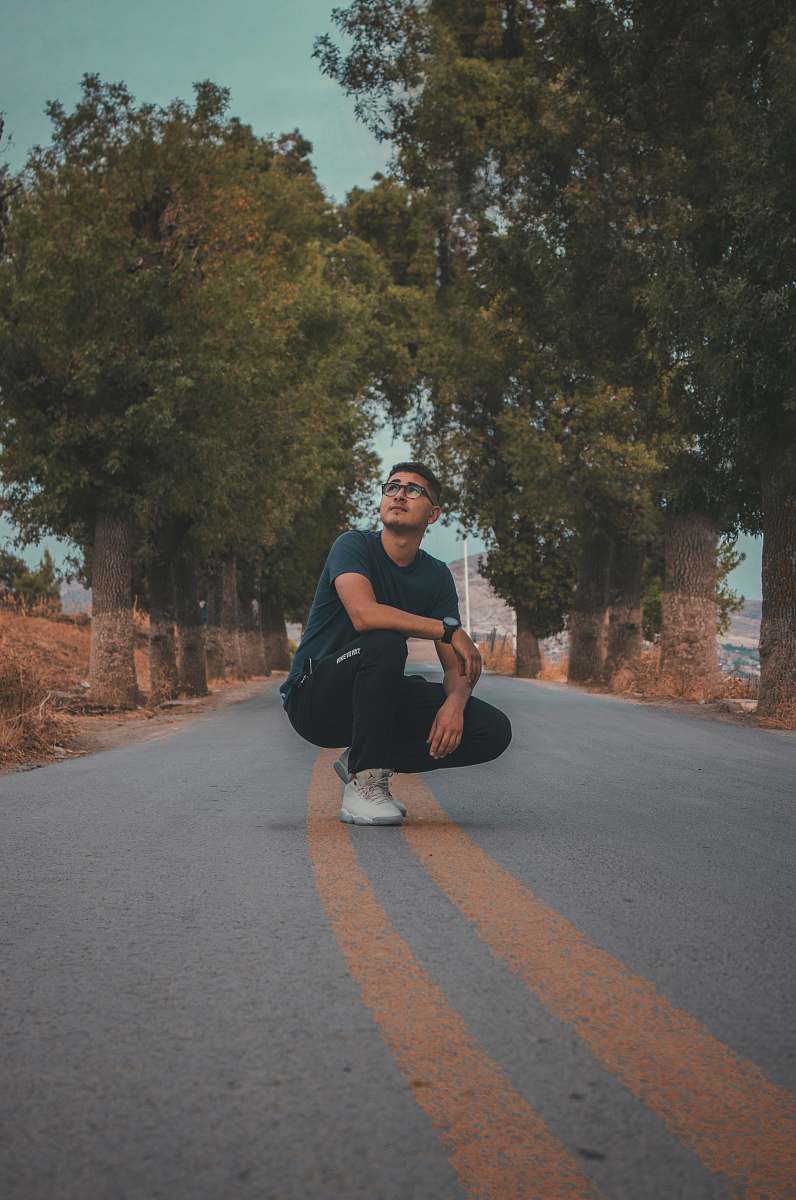apparel man crouching in middle of road footwear