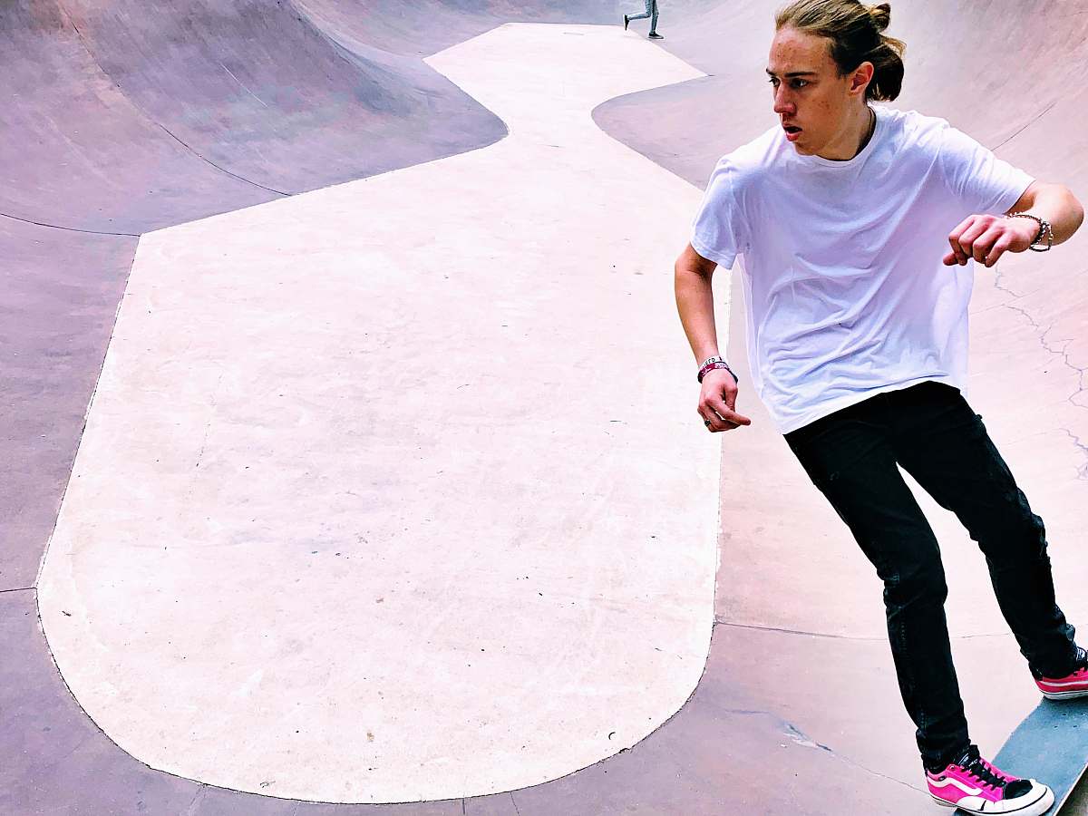 apparel man in white t-shirt and black denim jeans on skateboard in park footwear