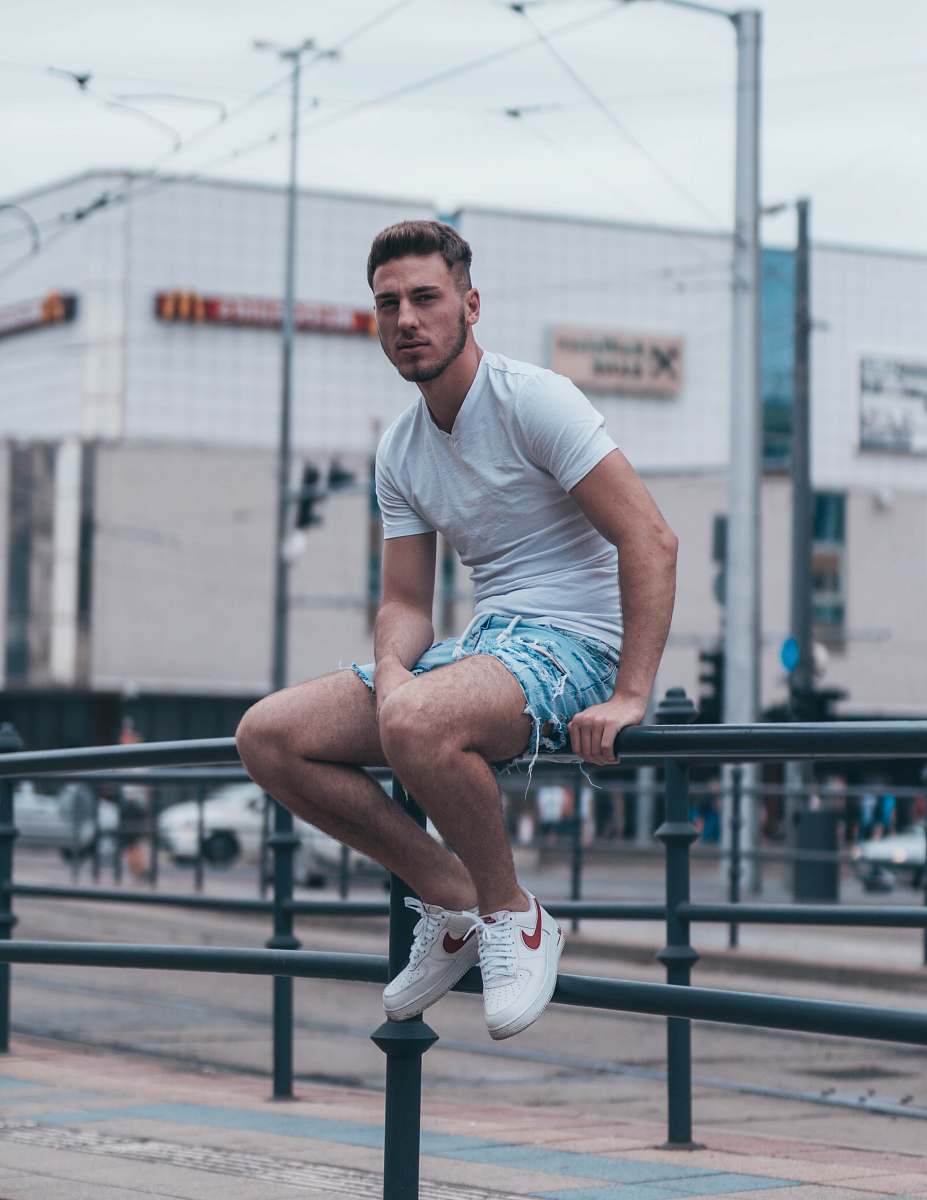 shorts man sits on metal railings apparel