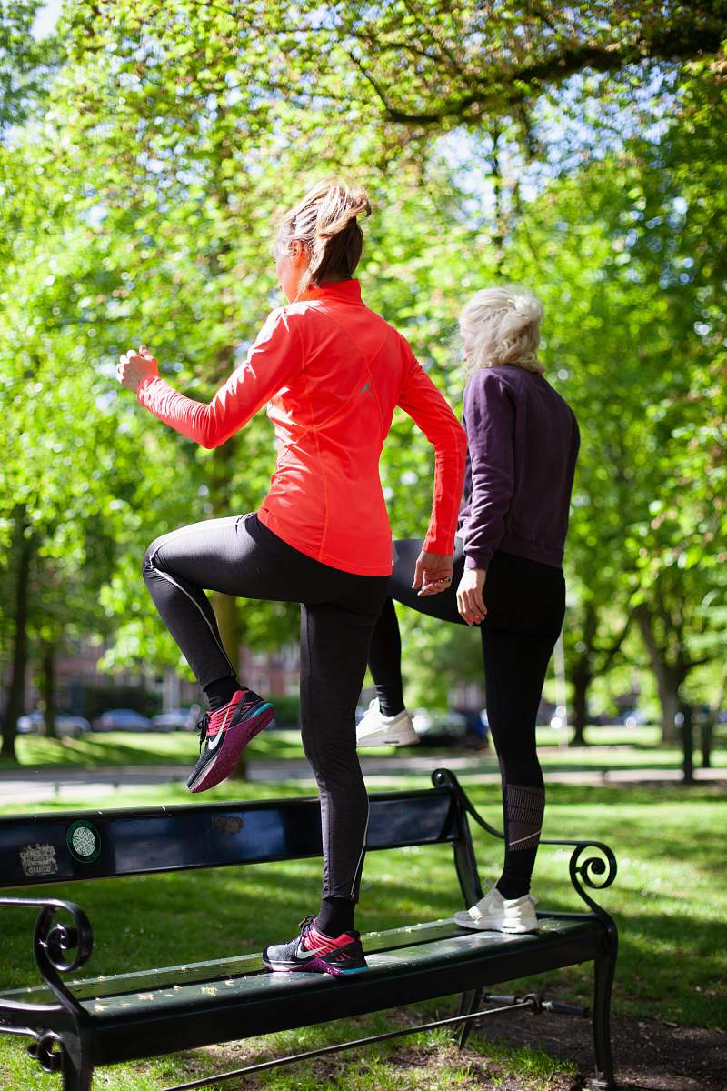 footwear photography of women standing on black bench near outdoor during daytime apparel