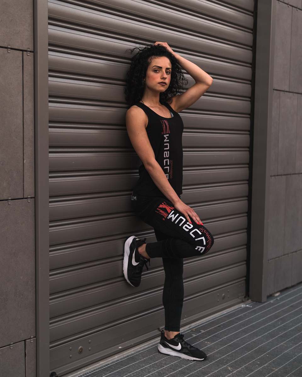 apparel woman standing against the wall and touching her hair human
