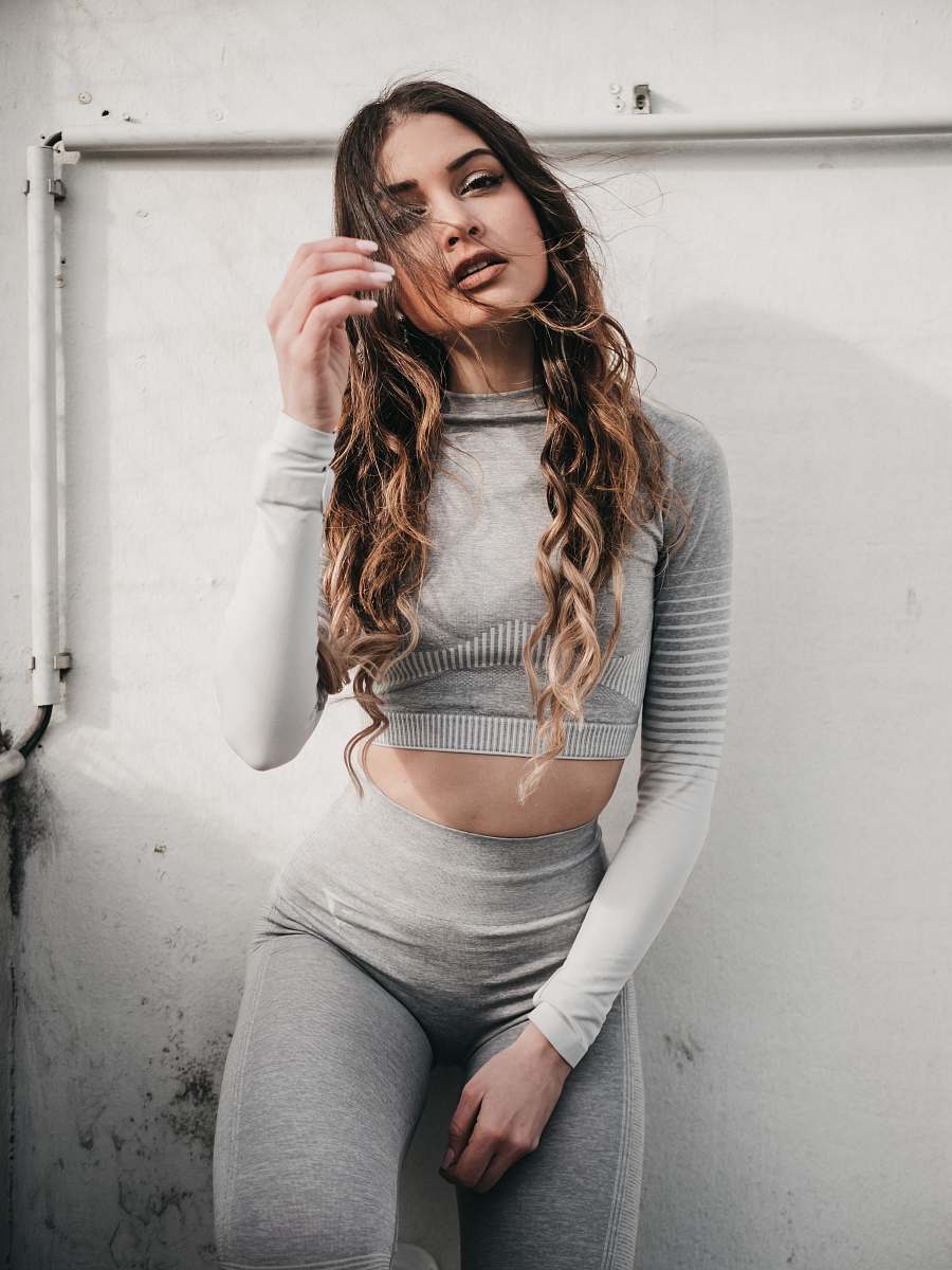 apparel woman wearing grey long-sleeved top leaning on wall sleeve