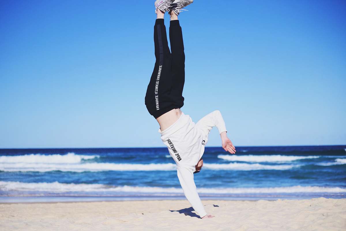 sport man doing cartwheel on sand fitness