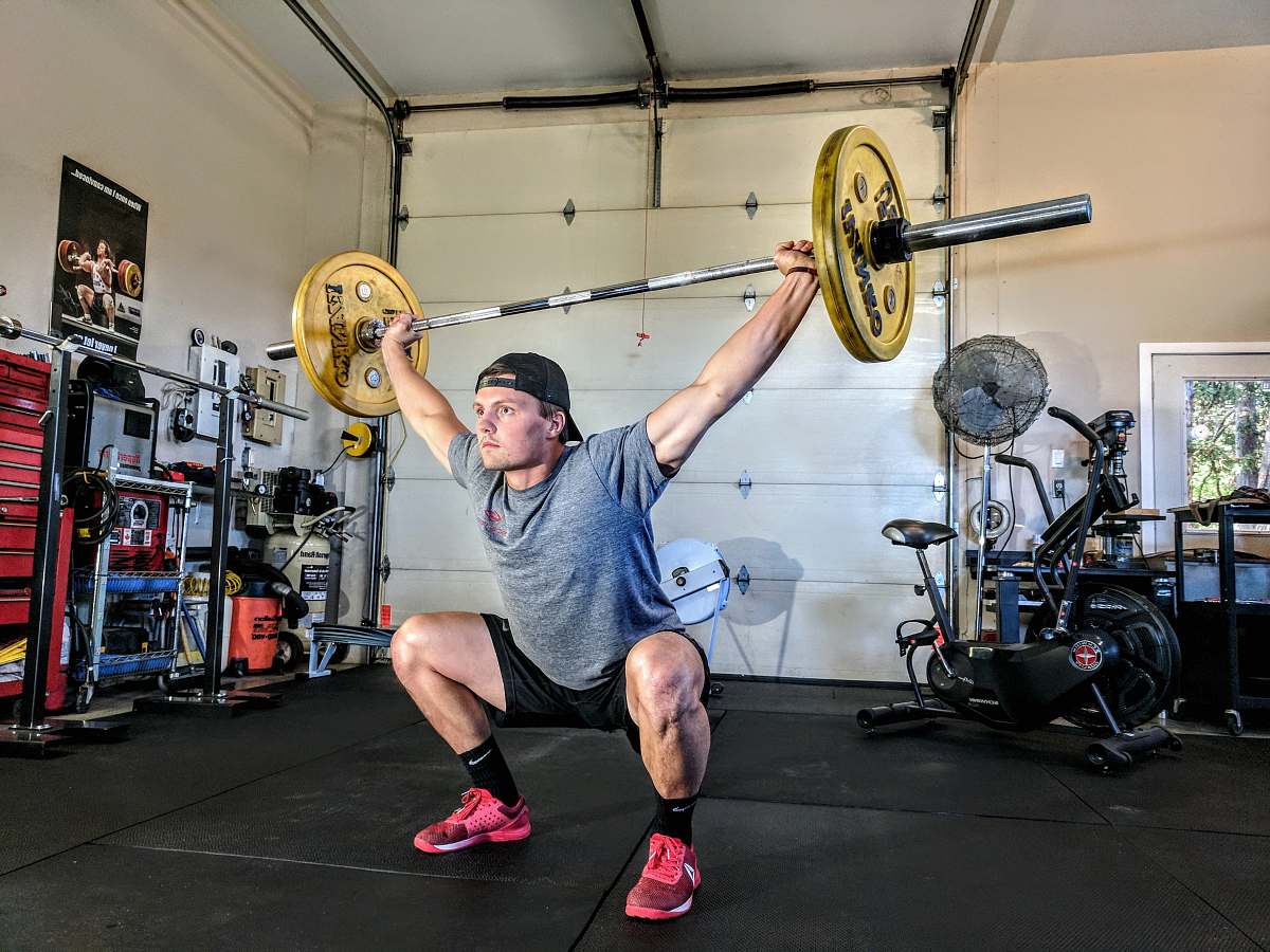 human man lifting yellow barbell people