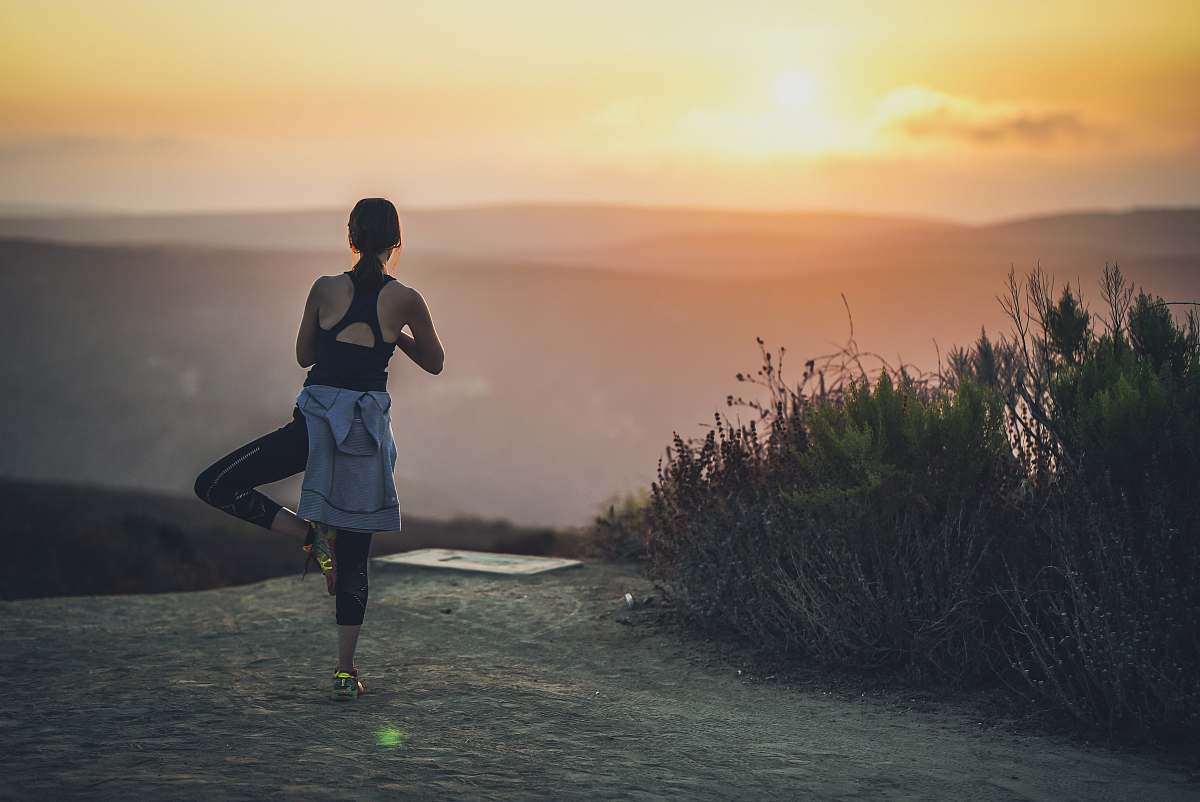 sports woman doing yoga post during golden hour jogging