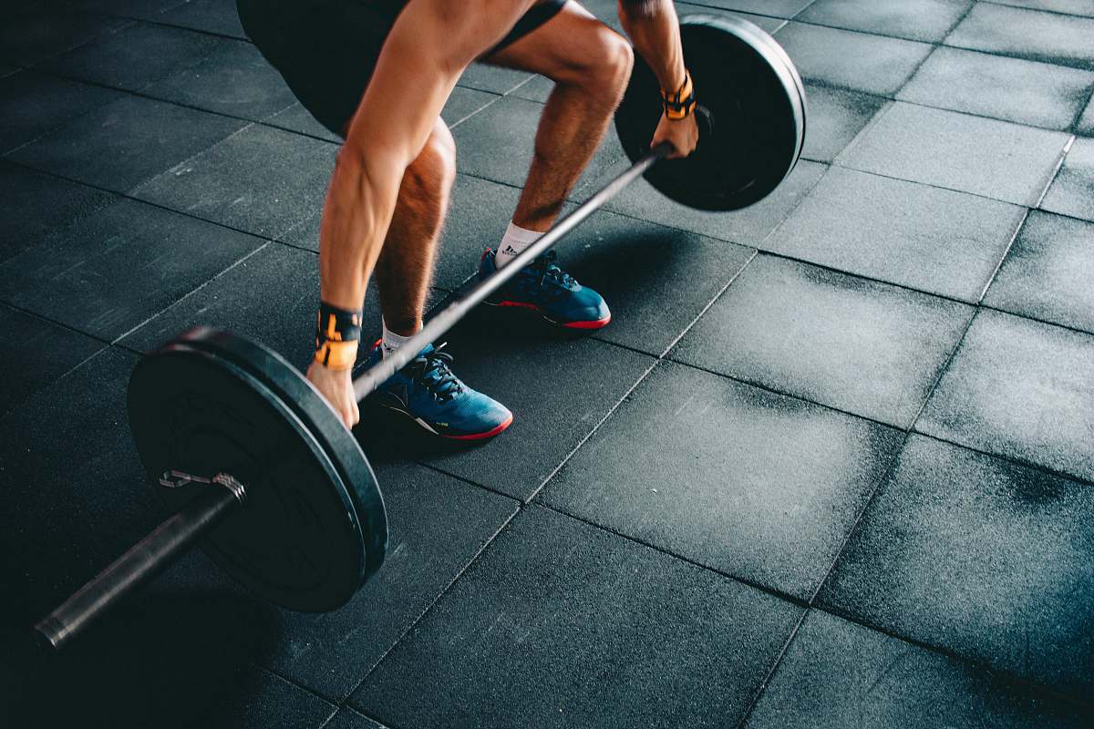 gym person holding black barbell footwear