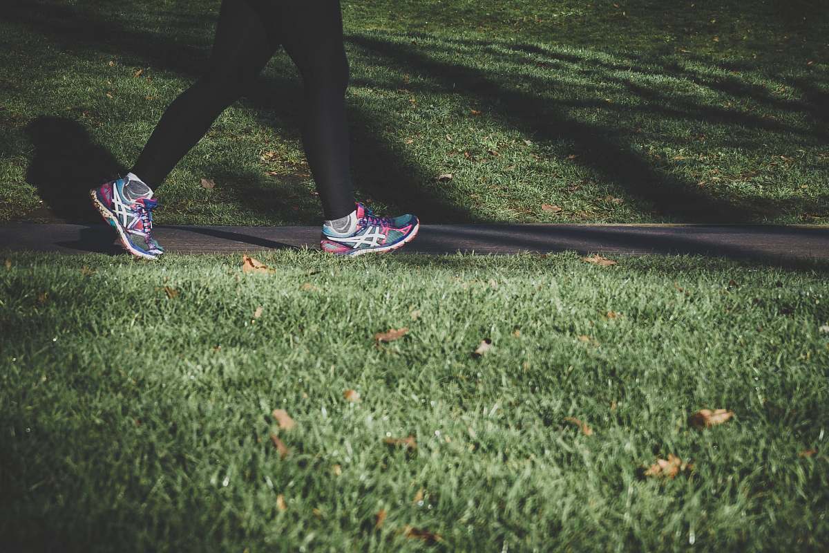 running shallow focus photography of person walking on road between grass health