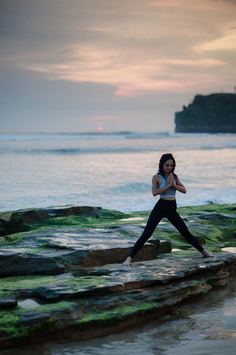 people woman doing yoga on rock platform next to body of water yoga