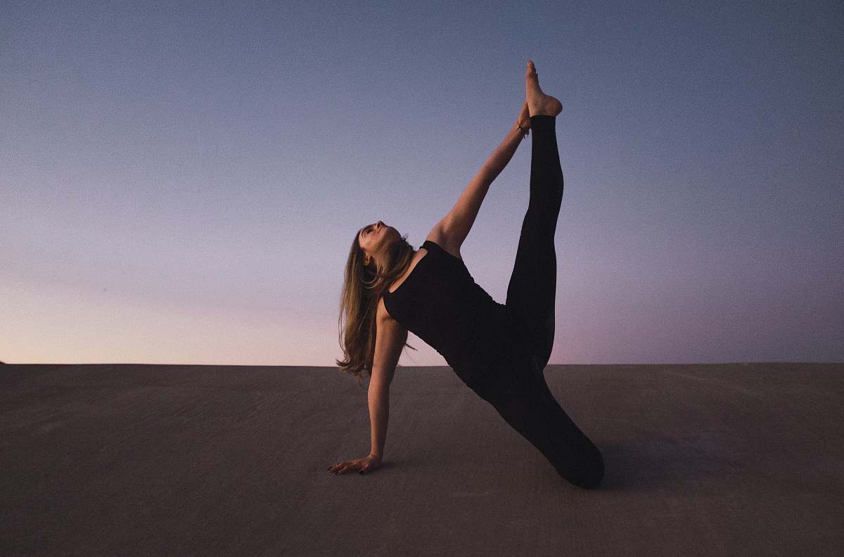 human woman holding her left leg high kneeling on floor person