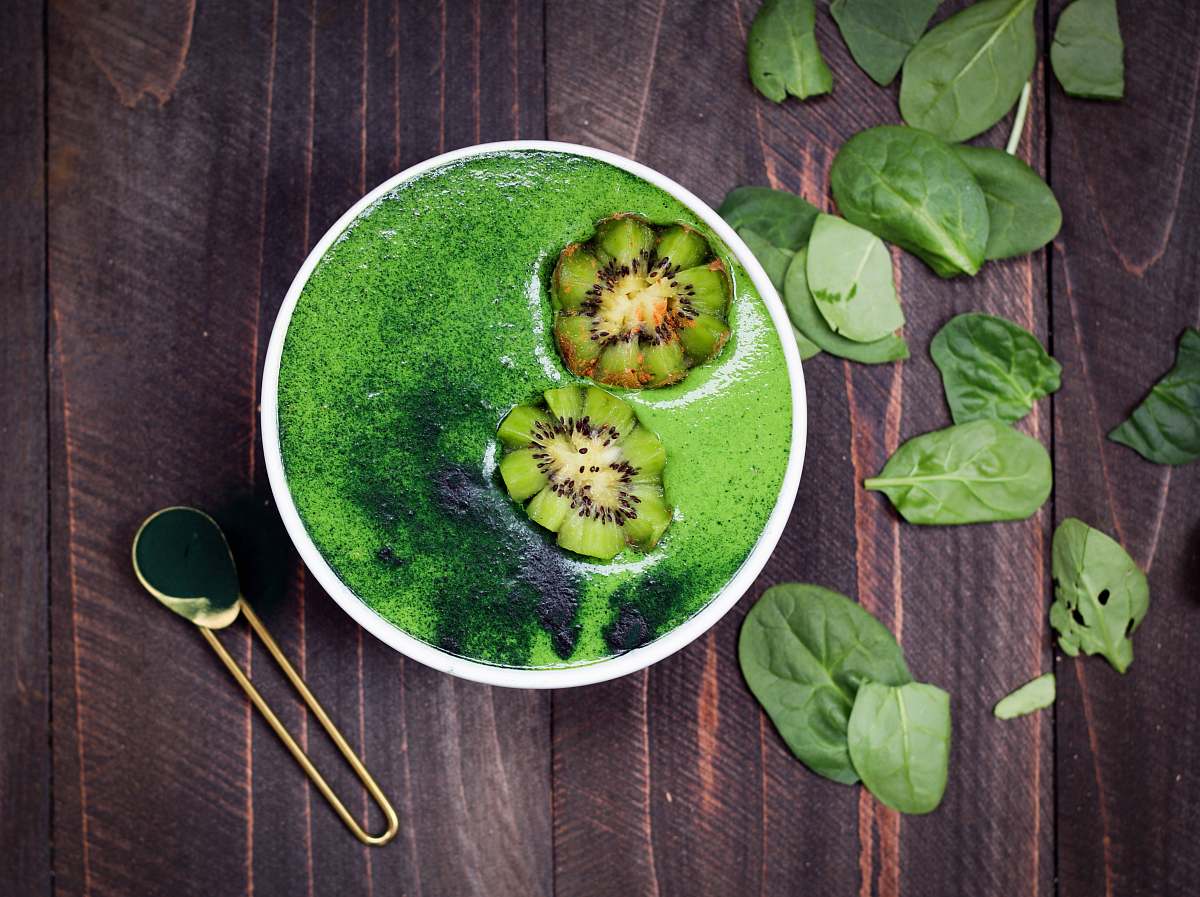 green green liquid in white ceramic container with brass-colored spoon on brown wooden surface vegetable
