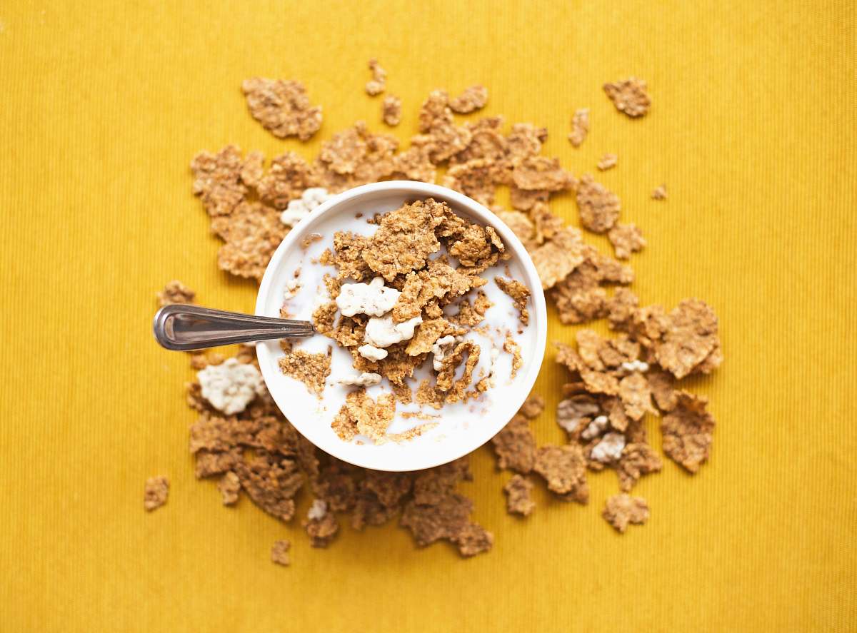 yellow top view of corn flakes in bowl with milk and silver spoon cereal
