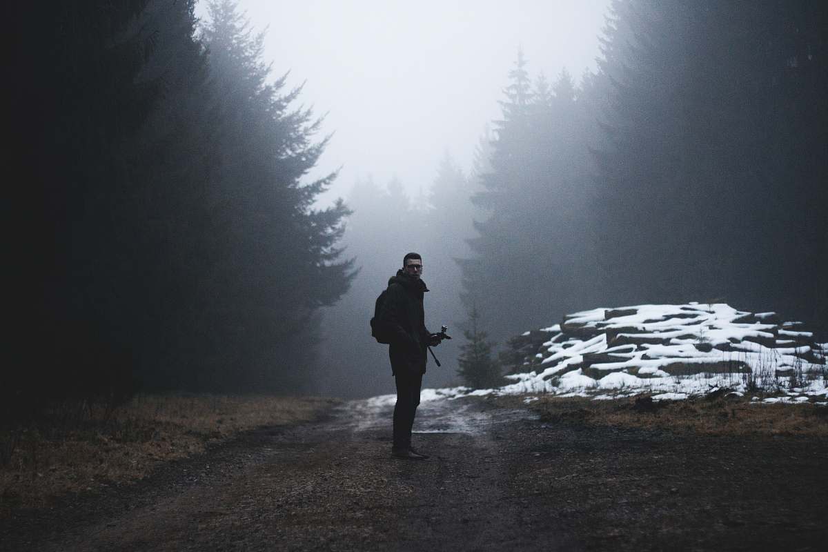 trees man standing on a wet road snow