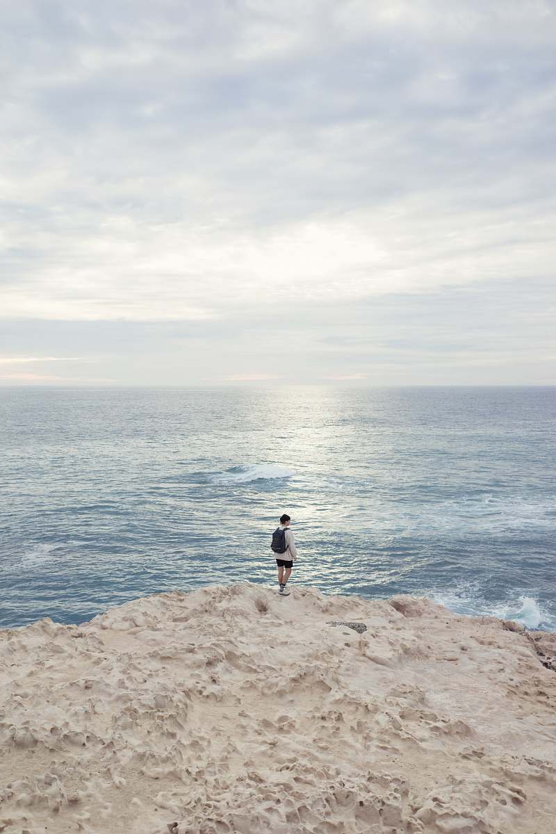 ocean person standing on the edge of the cliff near ocean sea