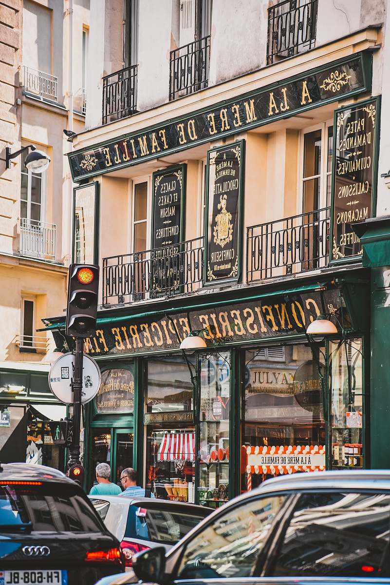 Immerse yourself in the enchanting ambiance of a Parisian street, featuring a vibrant Confiserie and Epicerie. This scene captures the essence of city life, with a stylish car parked nearby and the delightful aromas of freshly baked pastries and gourmet goods wafting through the air. Perfect for showcasing the allure of Paris, this image is ideal for travel blogs, lifestyle magazines, and culinary websites looking to evoke the romance and charm of French culture.
