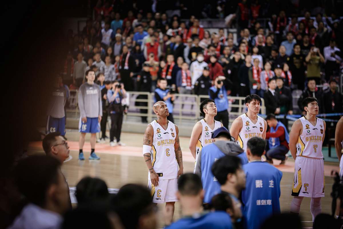 person four basketball players forming a line while standing on court surrounded by crowd people