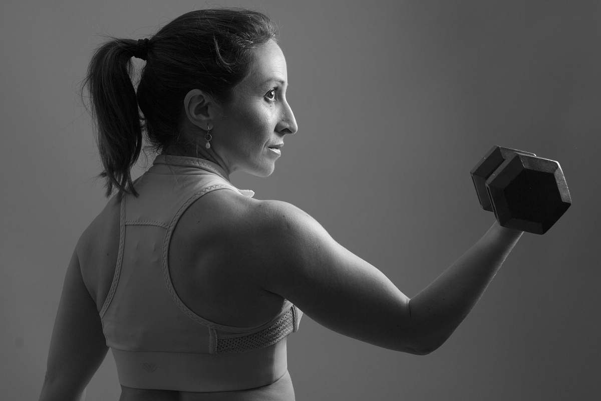 person grayscale of woman carrying dumbbell black-and-white