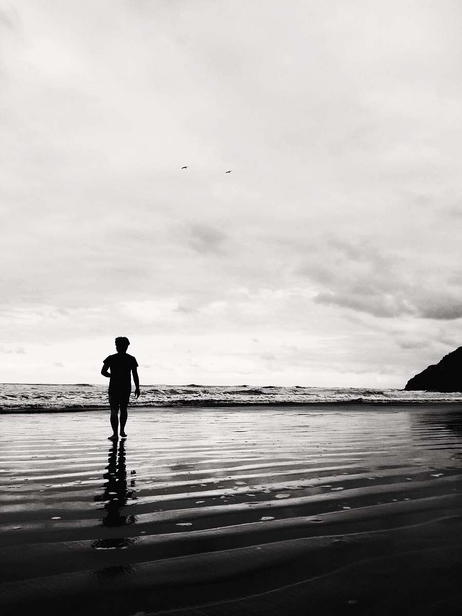 person grayscale photo of man on shore black-and-white